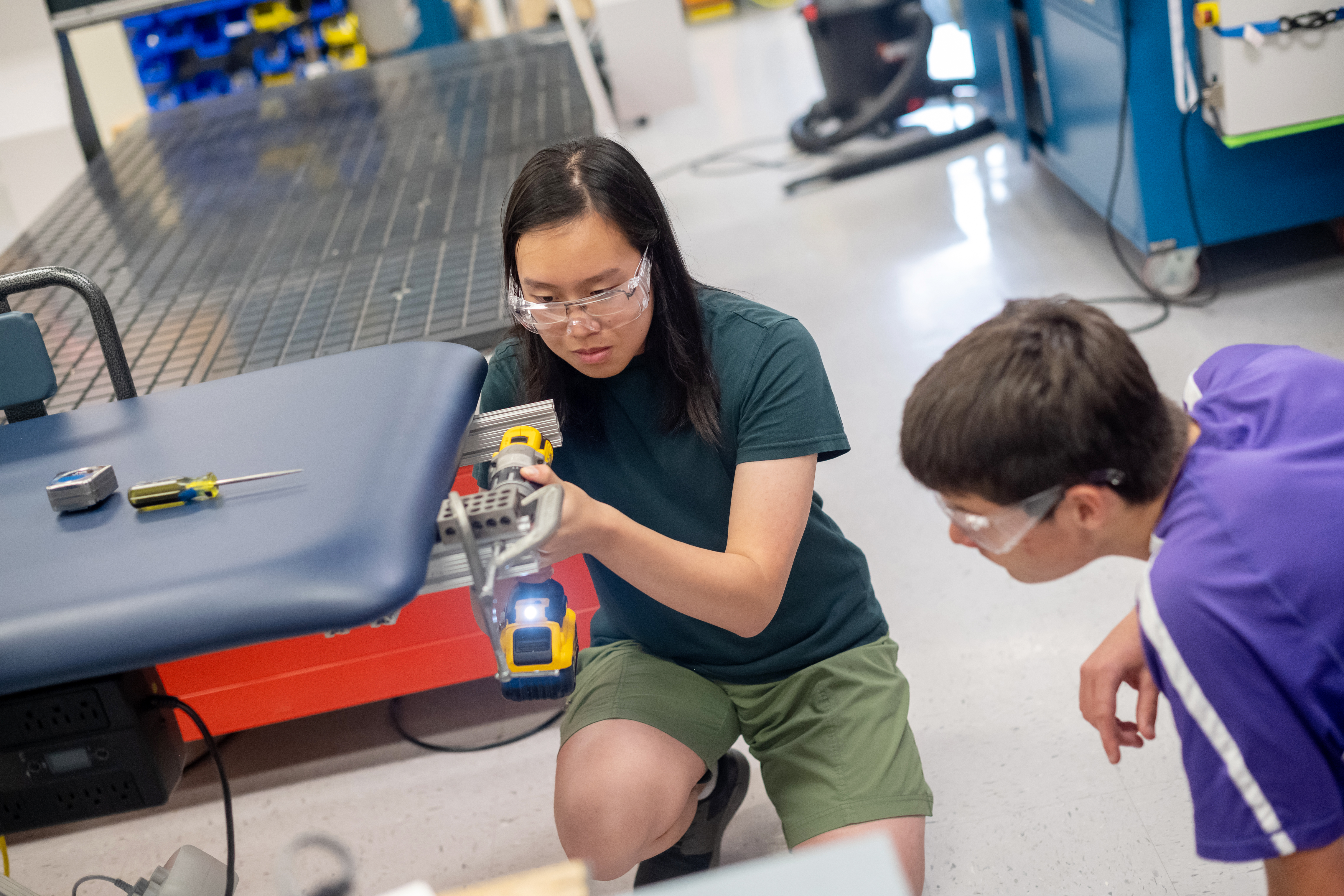 Engineering student Peter Nguyen works on the metal frame underneath the medical bed the students designed for a student with disabilities.