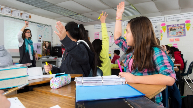 Students with hands raised in a classroom