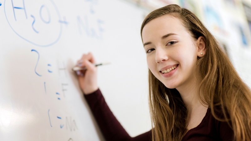 student at the board working on a Chemistry problem