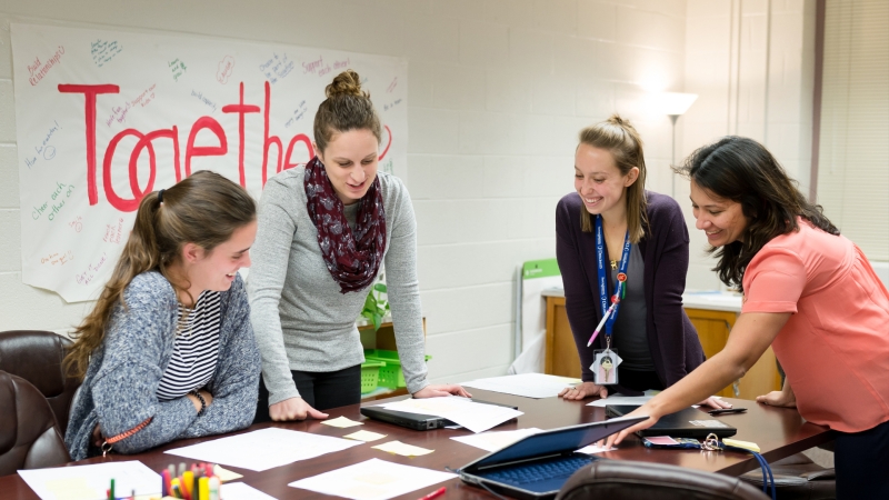 photo of four teachers standing around the table collaborating