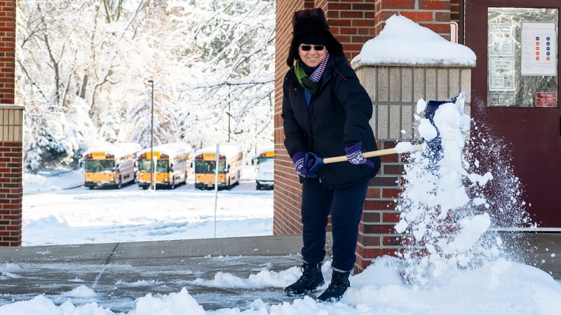 A worker shovels snow on school grounds