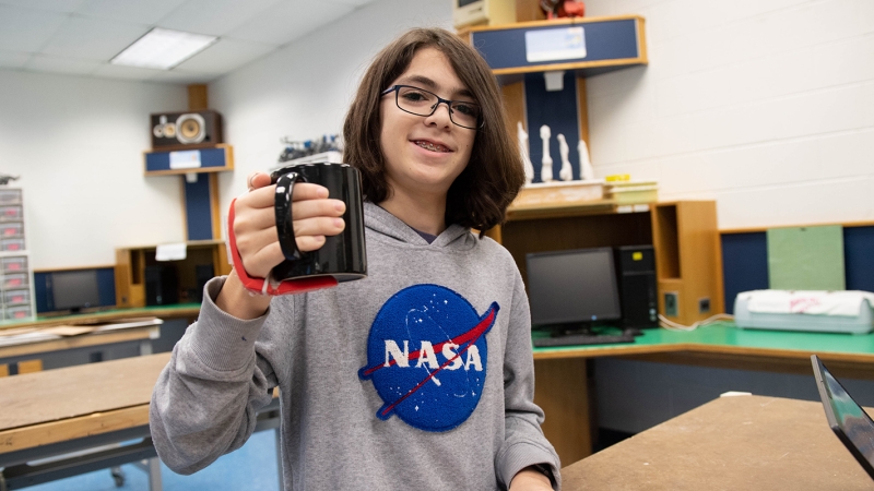 A student holds a prototype of a "third thumb"