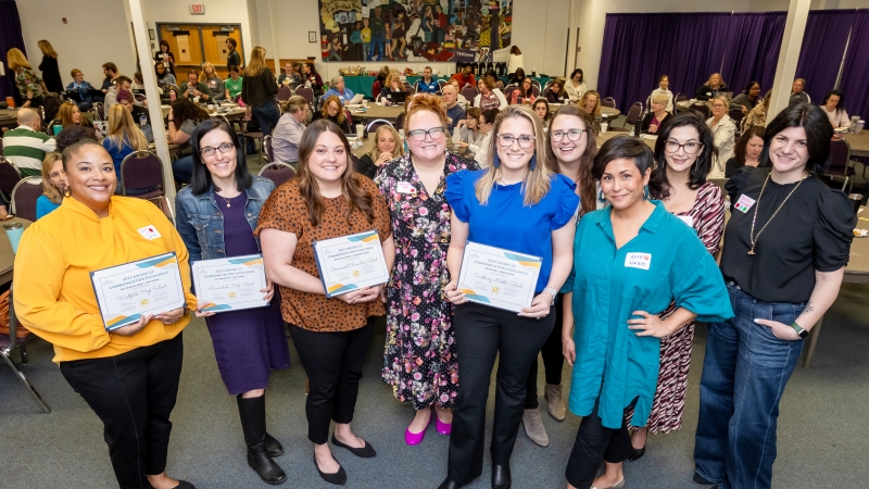 Award winners stand before a conference room