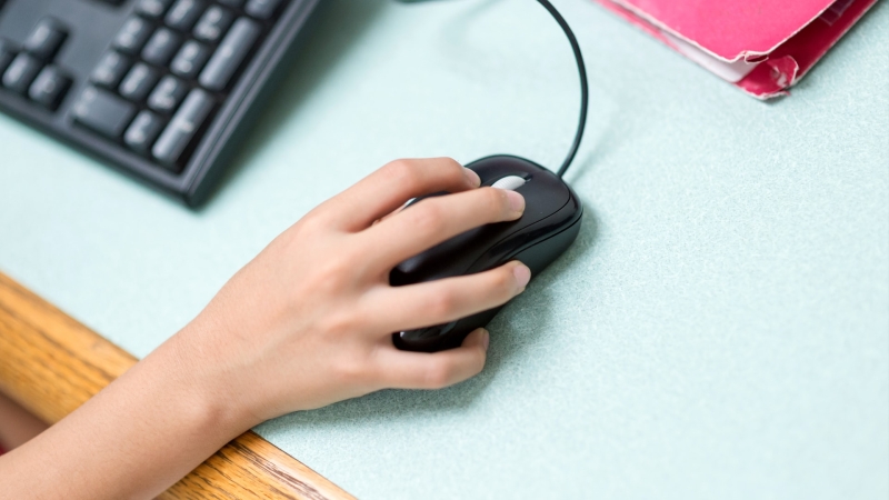 student's hand on an external mouse