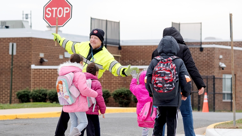 A crossing guard helps a student cross the street. 