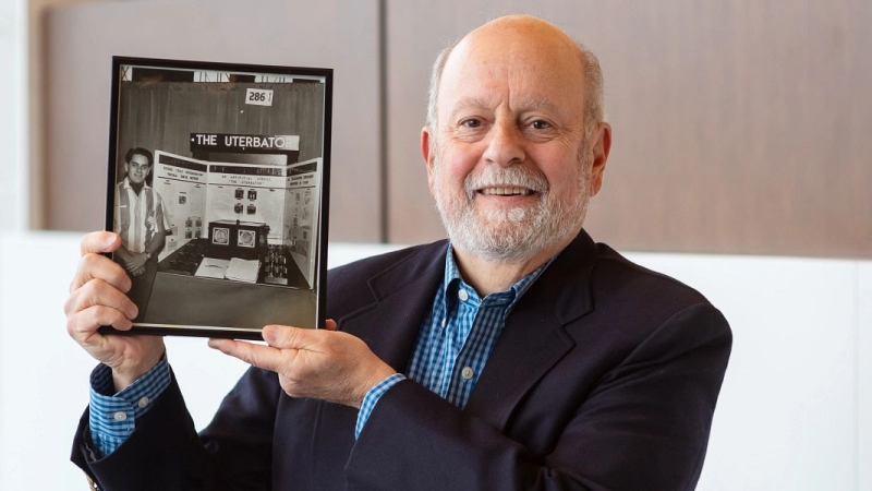 Dr. Chet Kessler, MD holds up a photograph of himself and his 1963 science project.