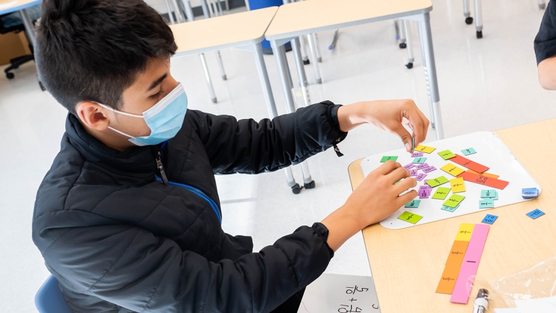 A student works with tiles to learn about fractions. 