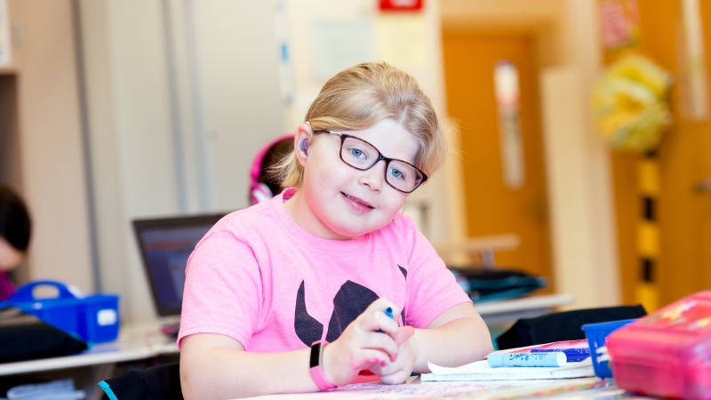 Student with a hearing aid sitting at her desk.