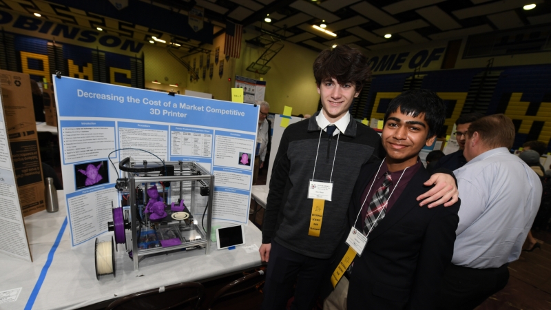 two students standing in front of their science fair project