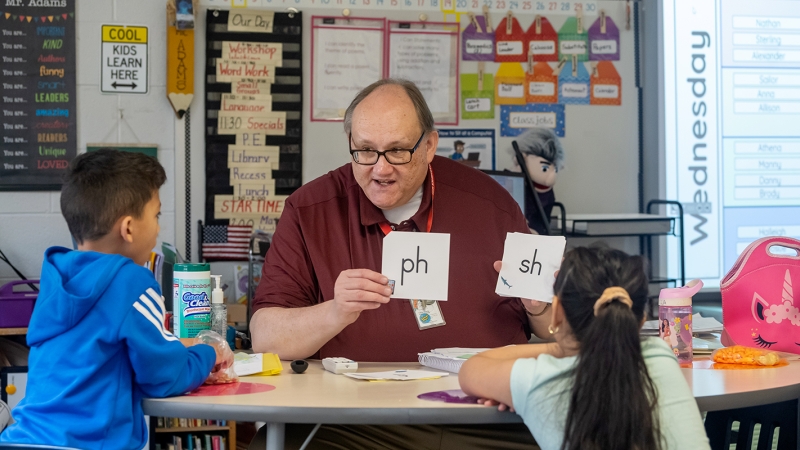 a teacher works with students using flash cards. 