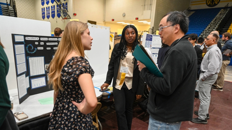 a student explaining their project to a science fair judge