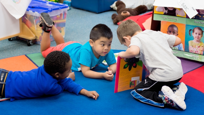 Children reading a book together on the floor