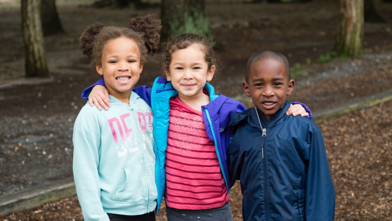 image of three kids standing outside smiling
