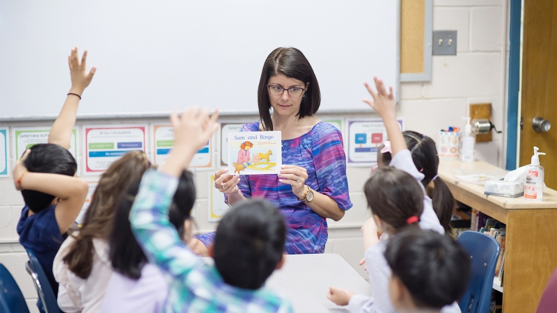 A teacher reads to students sitting around her. 