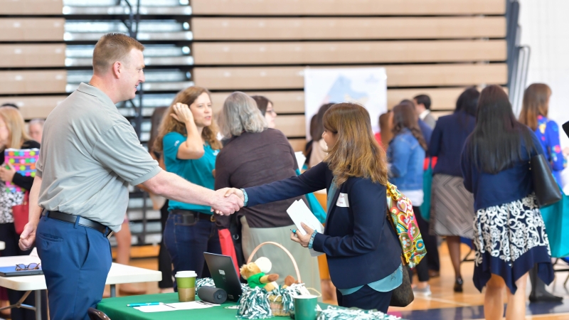 Two people shake hands at a FCPS instructional job fair. 