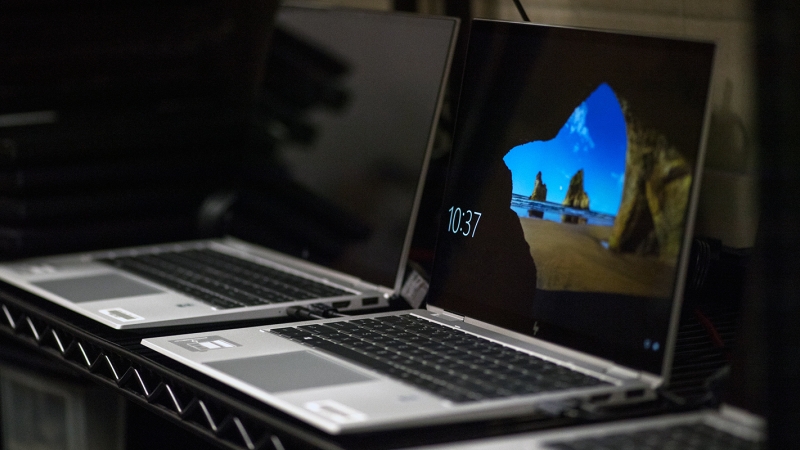 two laptops side by side in a darkened room.