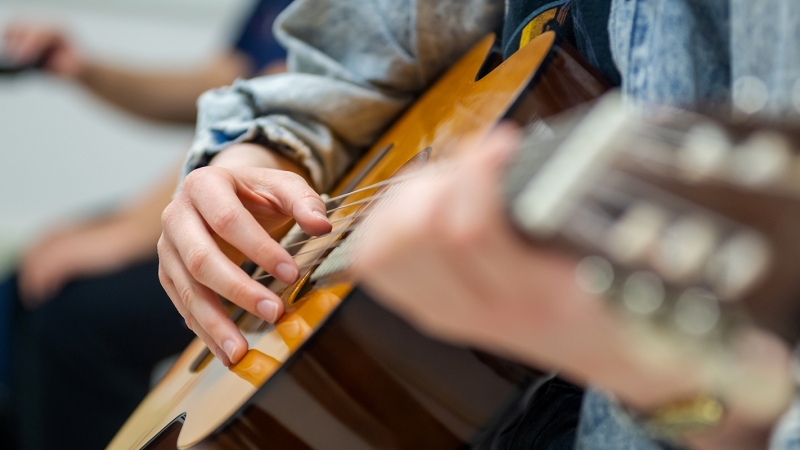 Closeup of a student's hand strumming a guitar