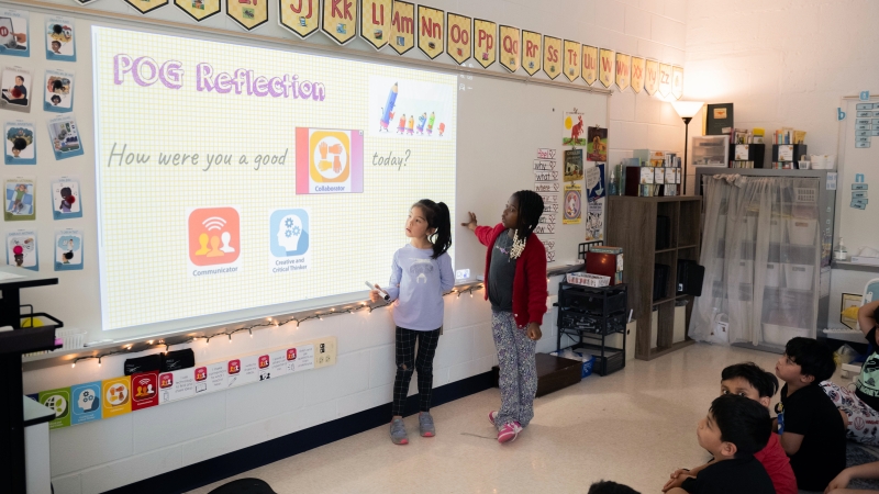 Students work at a smart board. 