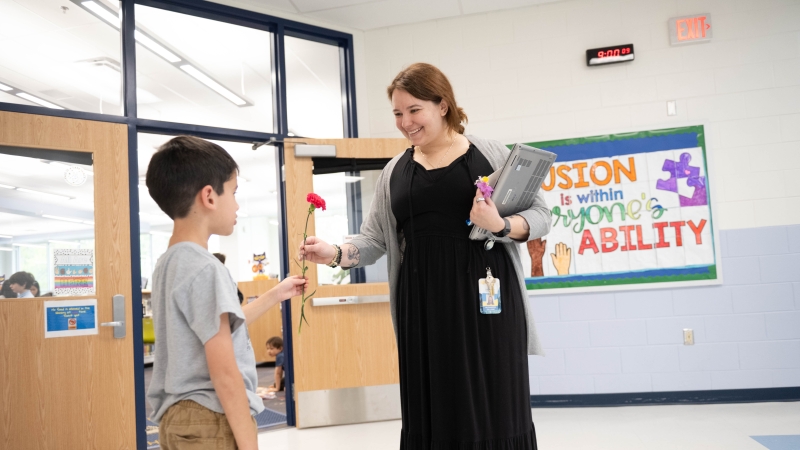 a student gives a teacher a flower. 