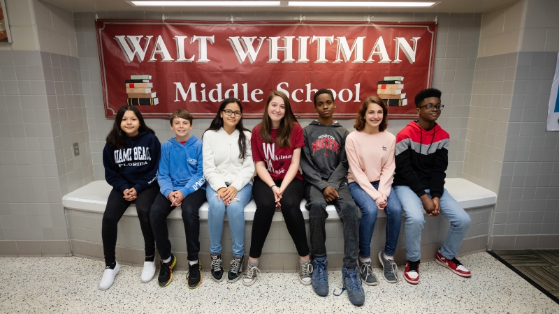 A group of diverse students standing in front of a Whitman MS sign