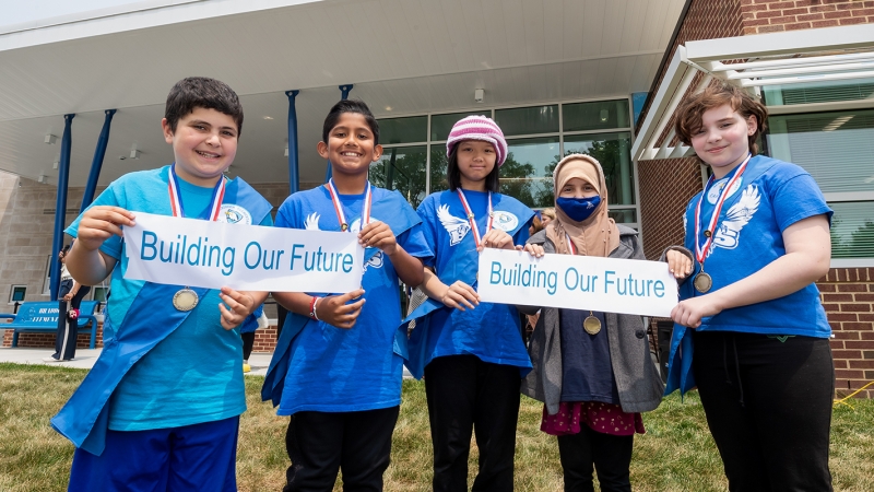 Four students holding Building Our Future ribbons