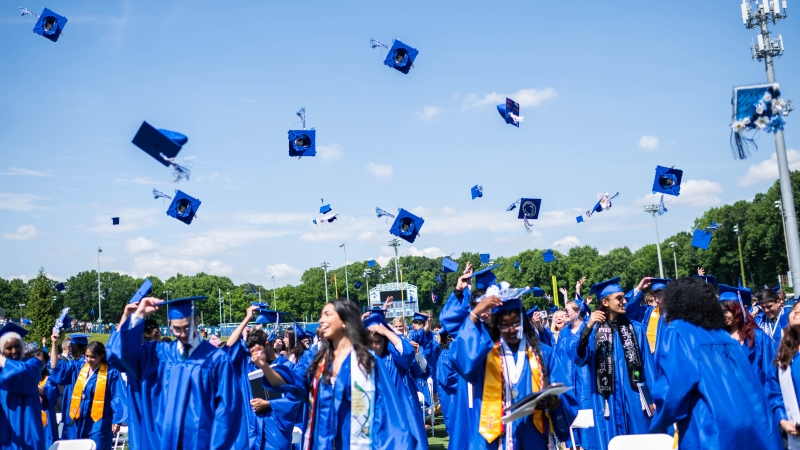 Students toss graduation caps. 