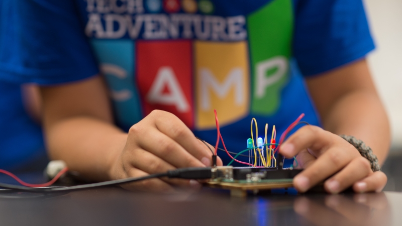 Student in blue shirt creating a circuit on a circuit board
