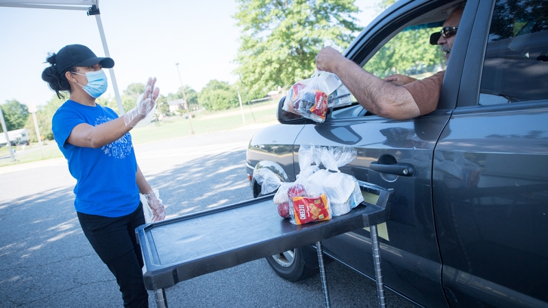 photo of food services staff handing meals through a car window
