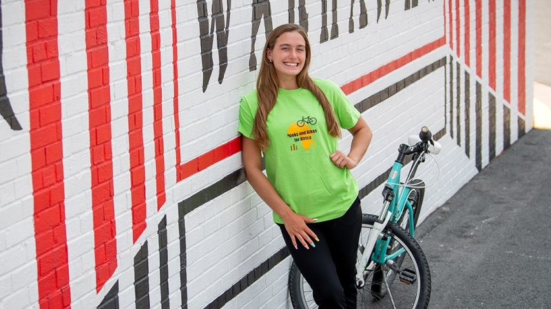 Sophia Brown standing outside Madison HS with her bike. 