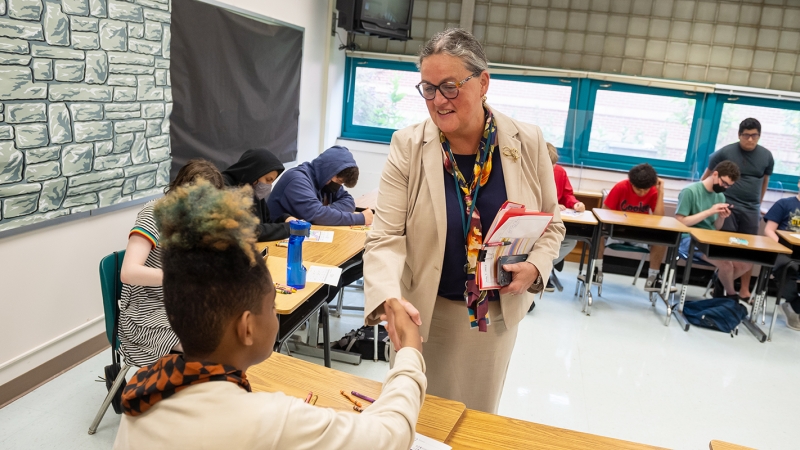 Superintendent Reid shaking a student's hand in a classroom. 