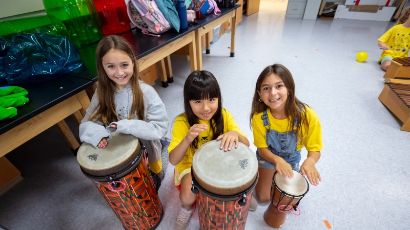 Three girls play drums