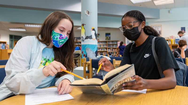 two female students reading a book