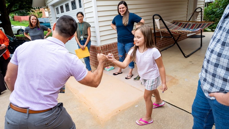 A student greets a teacher at a welcome walk. 