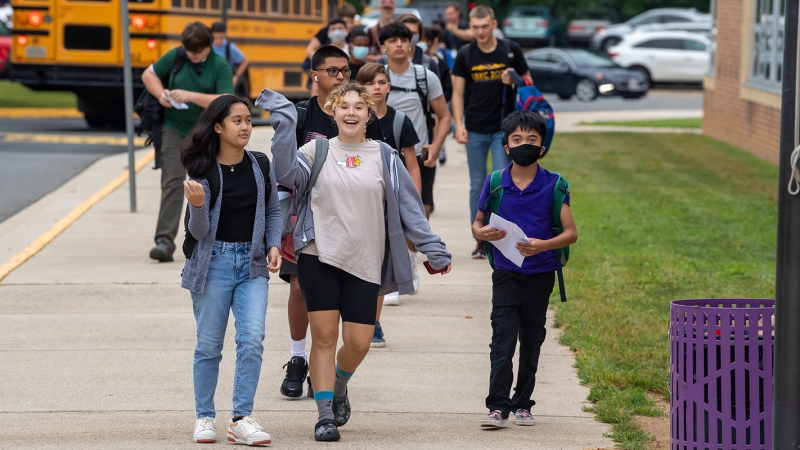 Happy students get off the bus on the first day of school. 