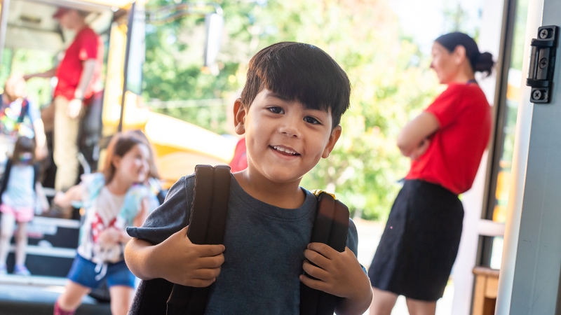 A smiling young boy walks into school