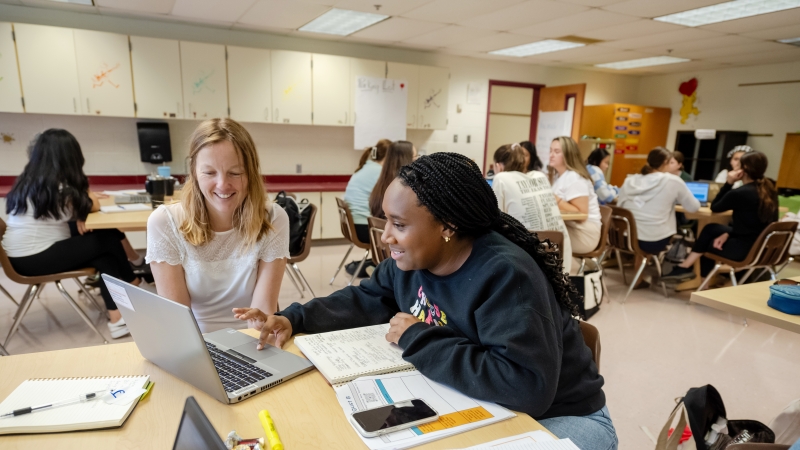 Two teachers work on a laptop