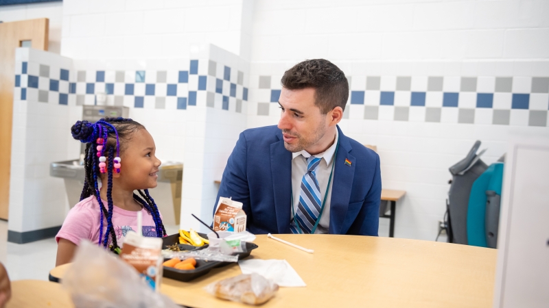 Sawko chatting with a student while she eats lunch.