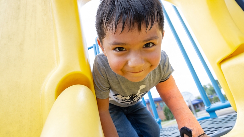 A young boy smiles going down a slide