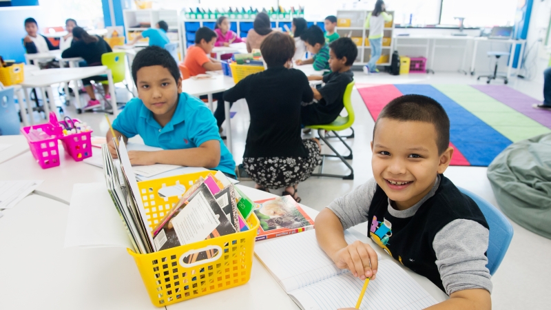 two young boys sitting in a classroom looking at the camera