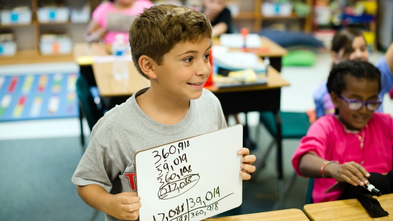 image of a boy holding a mini white board