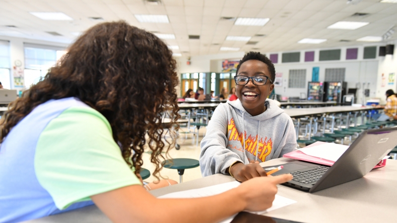 two students working on laptops