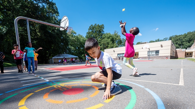 young students play on a colorful blacktop 