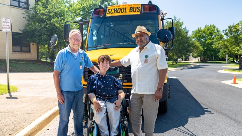 Mr. Ron, Shea Megale, and Mr. Bill in front of a School Bus