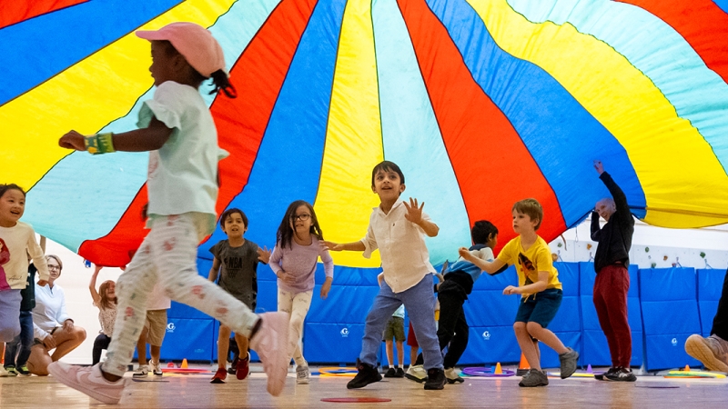 Students play under a parachute