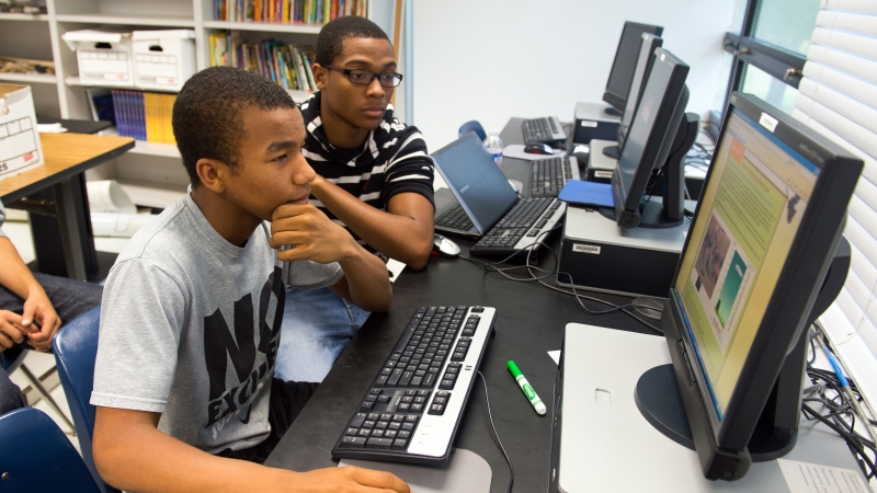 Two students working on an economics project on the computer.