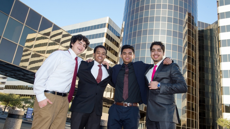 a group of four teenage boys dressed in suits standing in front of buildings