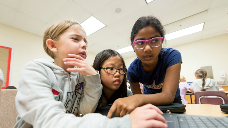 three students working together on one laptop