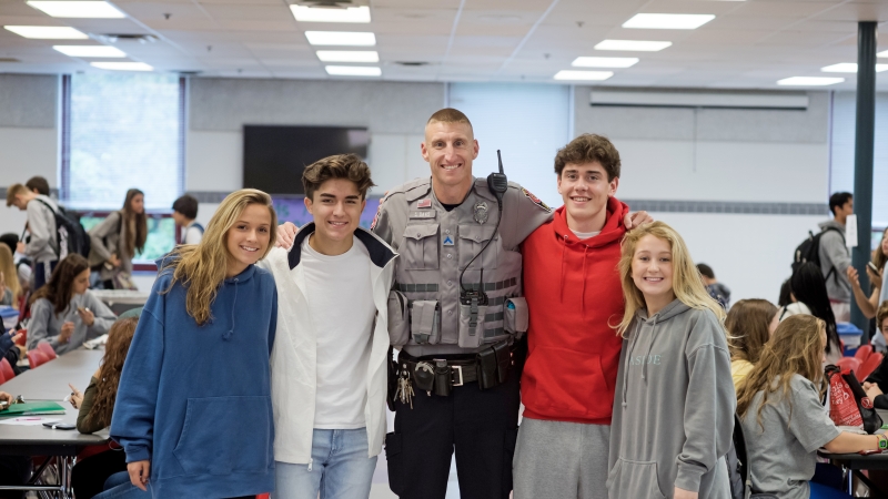 Image of a School Resource Officer standing in a cafeteria with four students