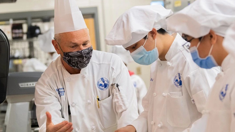 Culinary arts students work with their teacher in the kitchen.