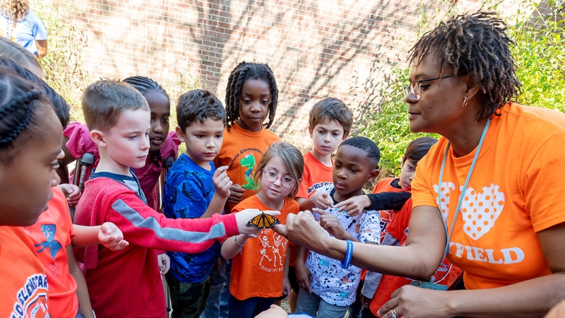 Students and teacher examining butterfly outside